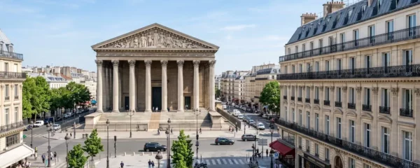 Vue large de la place de la Madeleine avec l'église Sainte-Marie-Madeleine et les immeubles haussmanniens sous un ciel lumineux