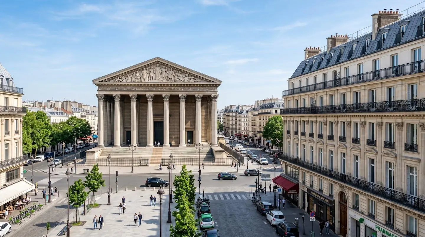 Vue large de la place de la Madeleine avec l'église Sainte-Marie-Madeleine et les immeubles haussmanniens sous un ciel lumineux